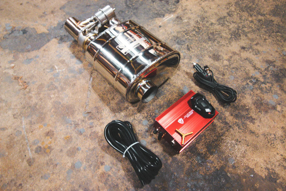 A side view of Valvetronic Designs UNIVERSAL Valved Muffler Kit on the ground with wires and red box.
