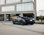 Grey Audi R8 rear three-quarter with carbon rear wing outside an office building
