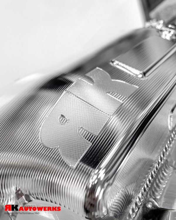 A close up view of Unfinished Aluminum of the RK Autowerks S58 BILLET PORT INJECTION MANIFOLD on a table