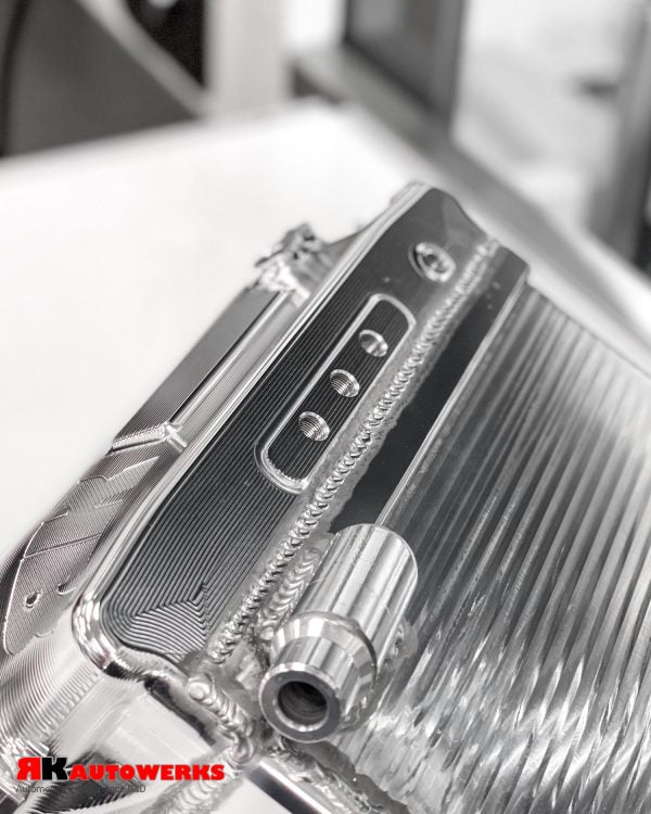 A close up view of Unfinished Aluminum of the RK Autowerks S58 BILLET PORT INJECTION MANIFOLD on a table