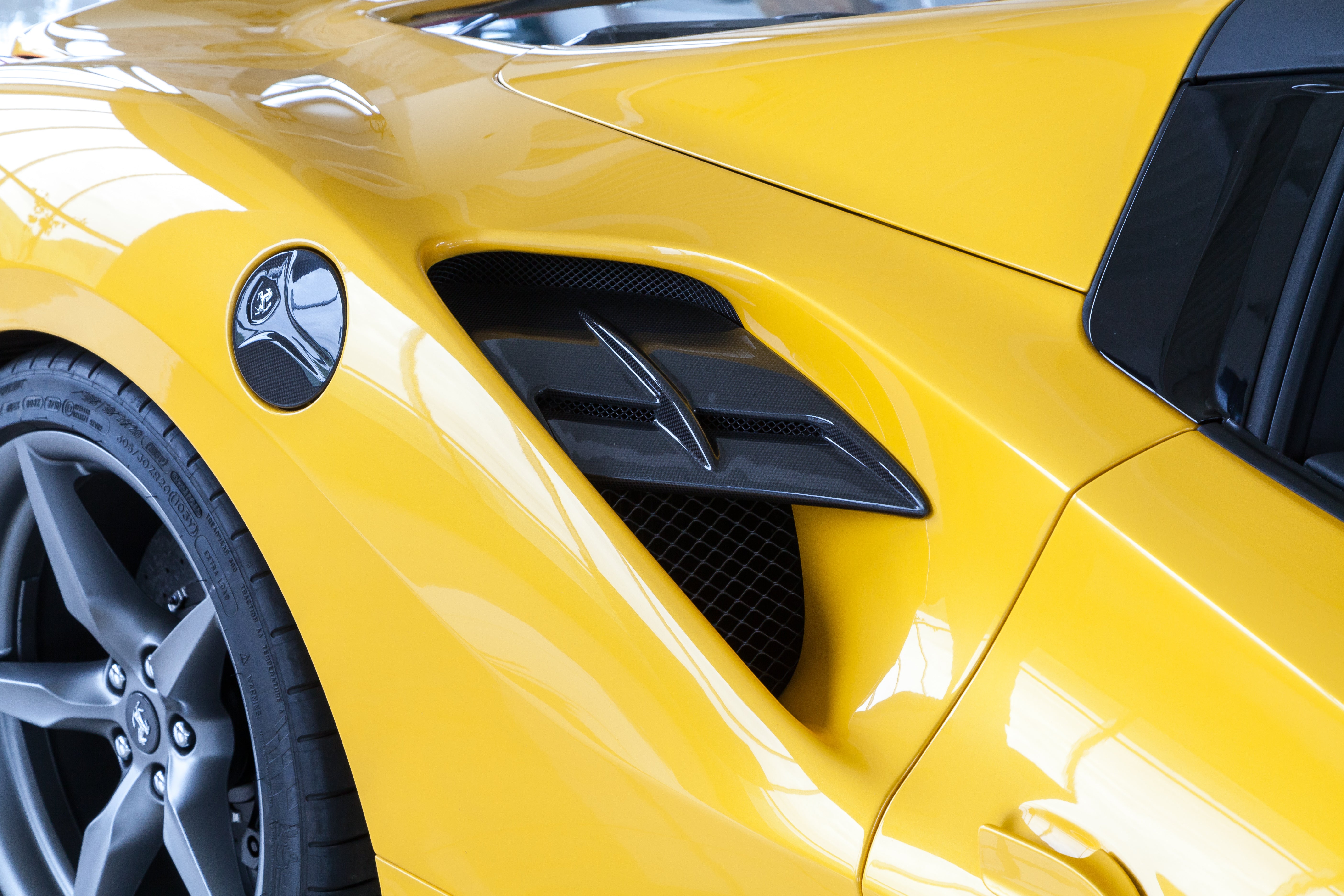 Capristo carbon fiber side air intake panel on a yellow Ferrari 488 by the fuel door