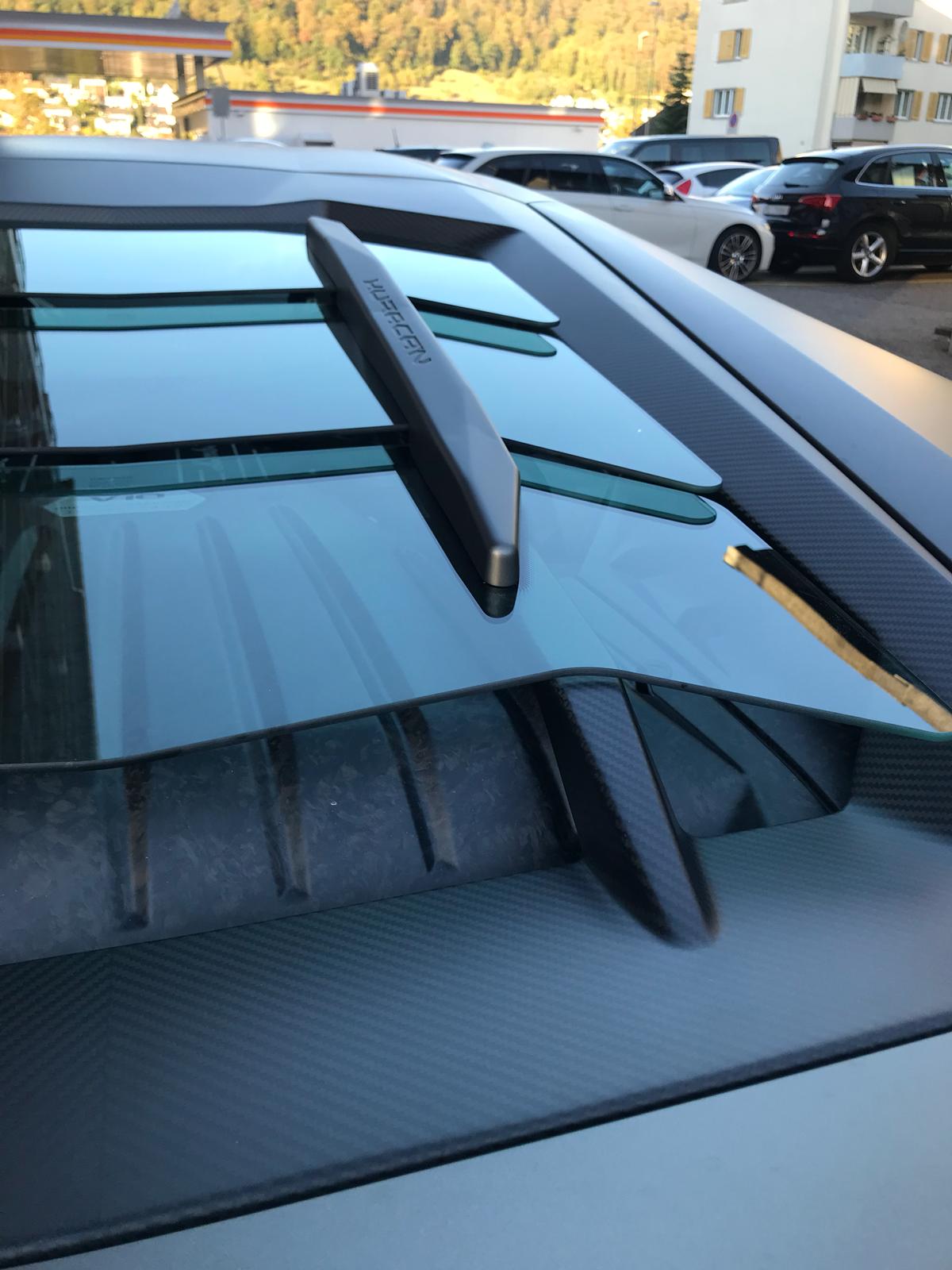 Close-up of glass and carbon slats of Capristo bonnet on matte grey Huracan