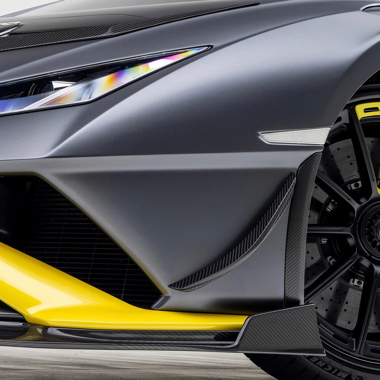 A side close up view of a car fitted with Vorsteiner Aero Canards Carbon Fiber for Lamborghini Huracan STO 2021-2025 on a white background