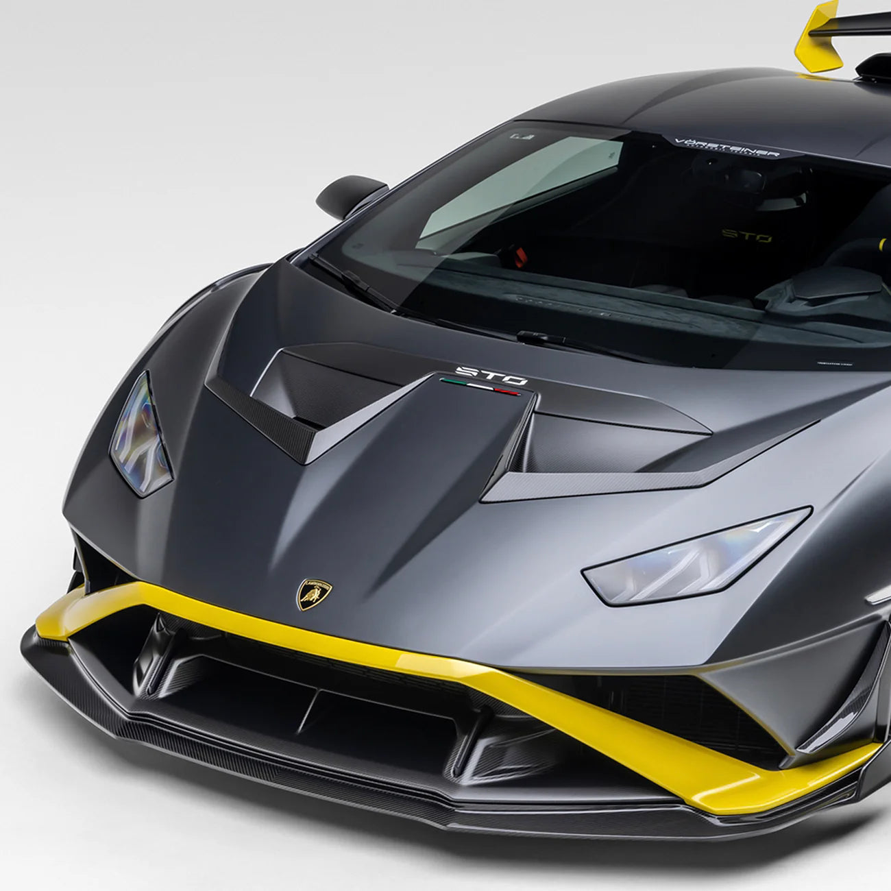 A side wide view of a car fitted with Vorsteiner Aero Hood Ducts Carbon Fiber for Lamborghini Huracan STO 2021-2025 on a white background