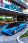 Blue McLaren 720S with carbon race hood under a building