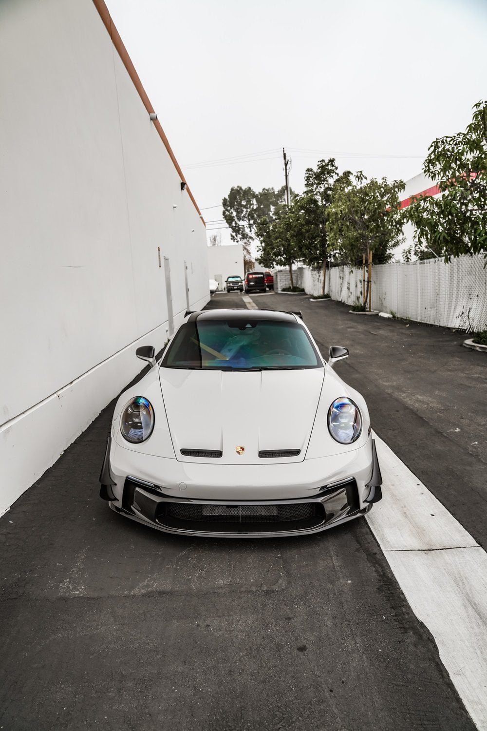 White Porsche 911 GT3 (992) front view with the 1016 vented hood in an alley
