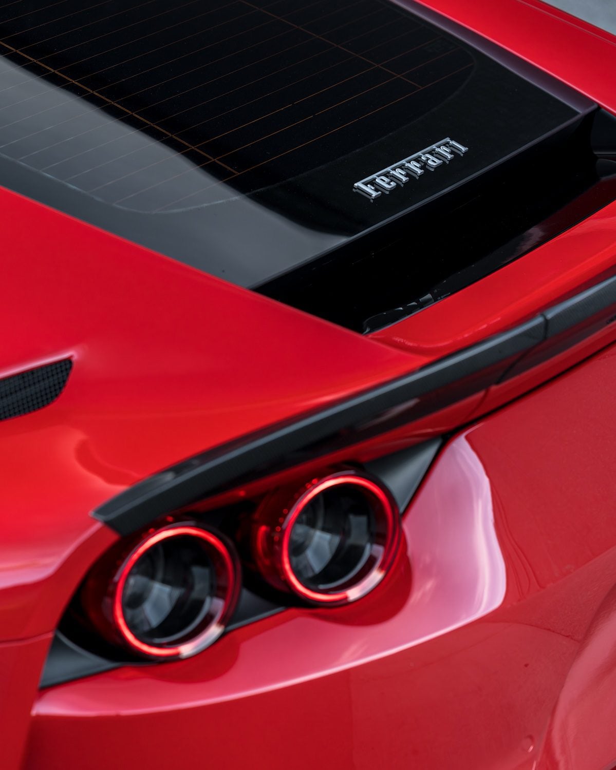 Carbon rear spoiler above the tail lights of a red Ferrari 812