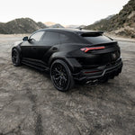 Black Lamborghini Urus rear three-quarter on a mountain road