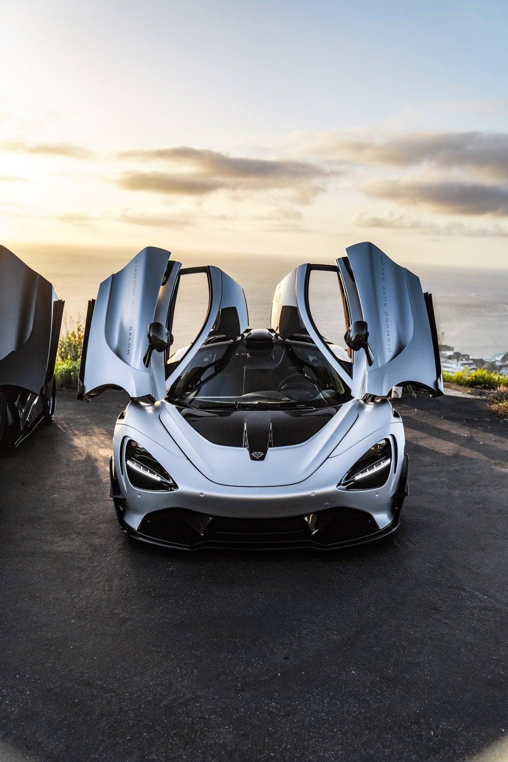 Silver McLaren 720S front view with the Vision package at sunset, doors up