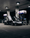 Silver McLaren 720S with the Vision package and doors up at a fuel station