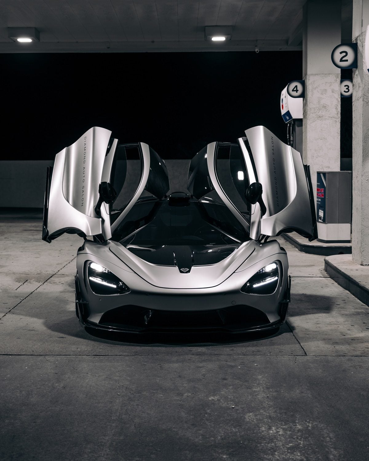 Silver McLaren 720S front view with the Vision package and doors up in a garage
