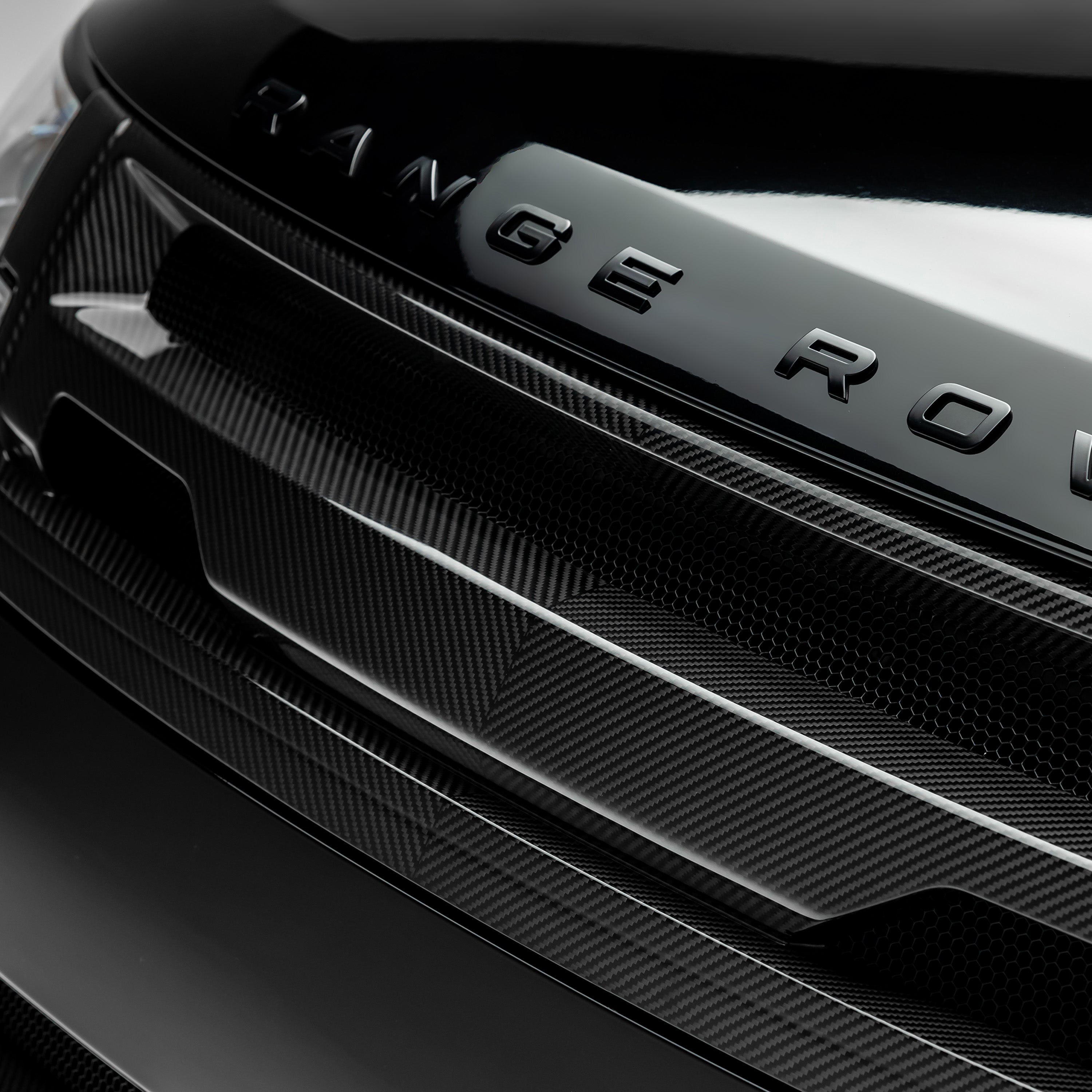 Gloss carbon L460 grille bar under hood lettering, macro