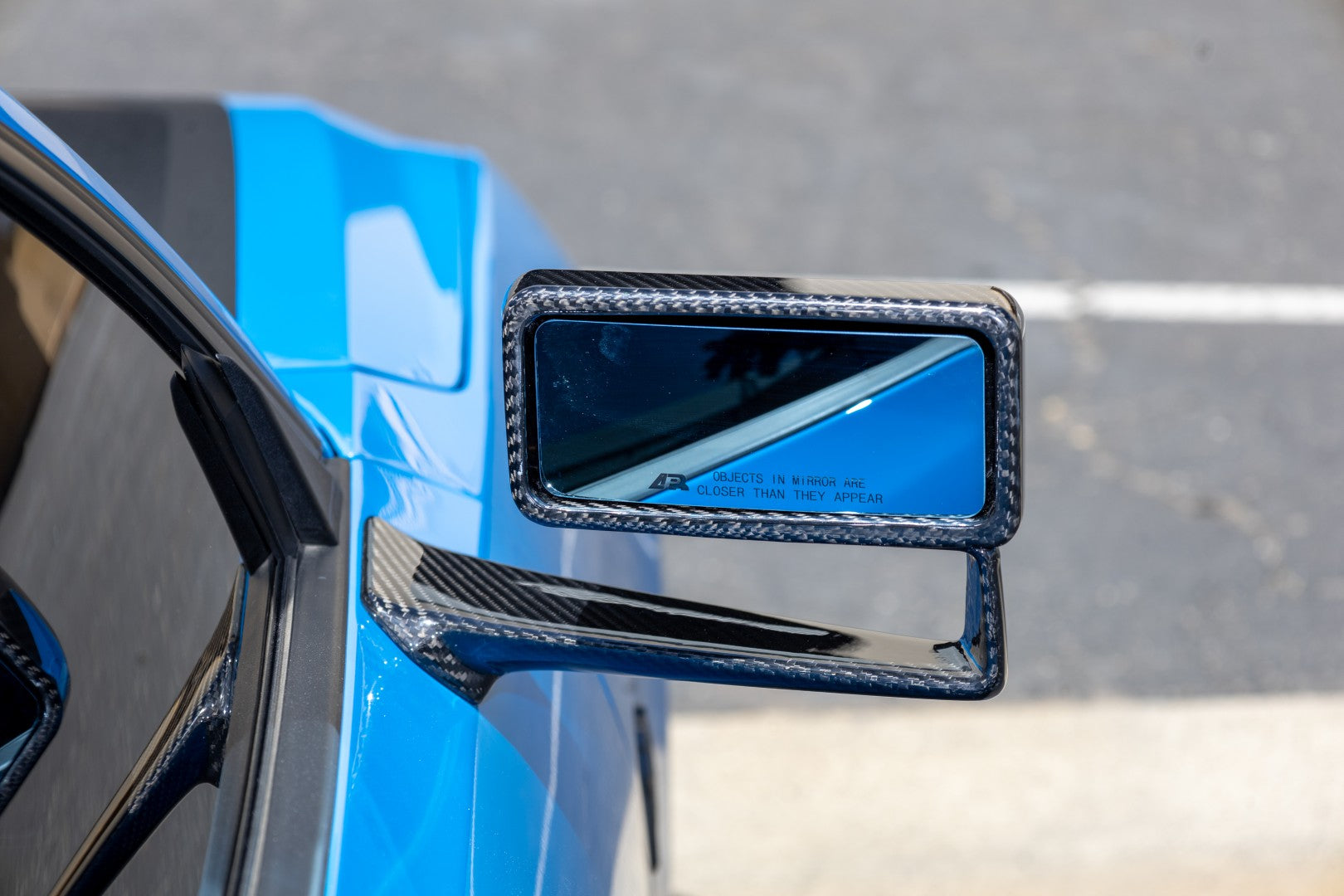 Carbon fiber side mirror assembly with rectangular mirror glass mounted on blue Mustang door - APR Performance side mirror for Ford S650 Mustang Dark Horse