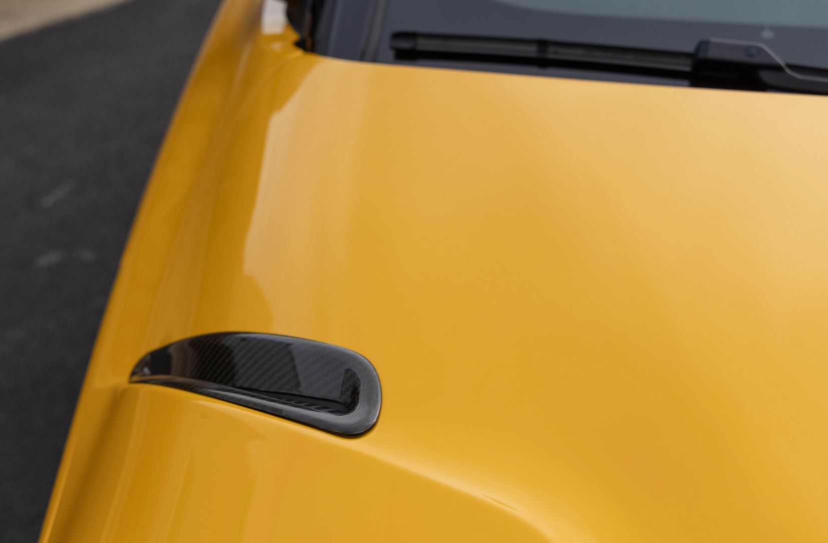 A close up view of a yellow car is fitted with Dinan Side Hood Vent Covers for Toyota GR Supra 2020-2025 on the road