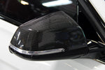 A close up view of one of the mirror of the Dinan Mirror Cap Set for BMW fitted on a white car