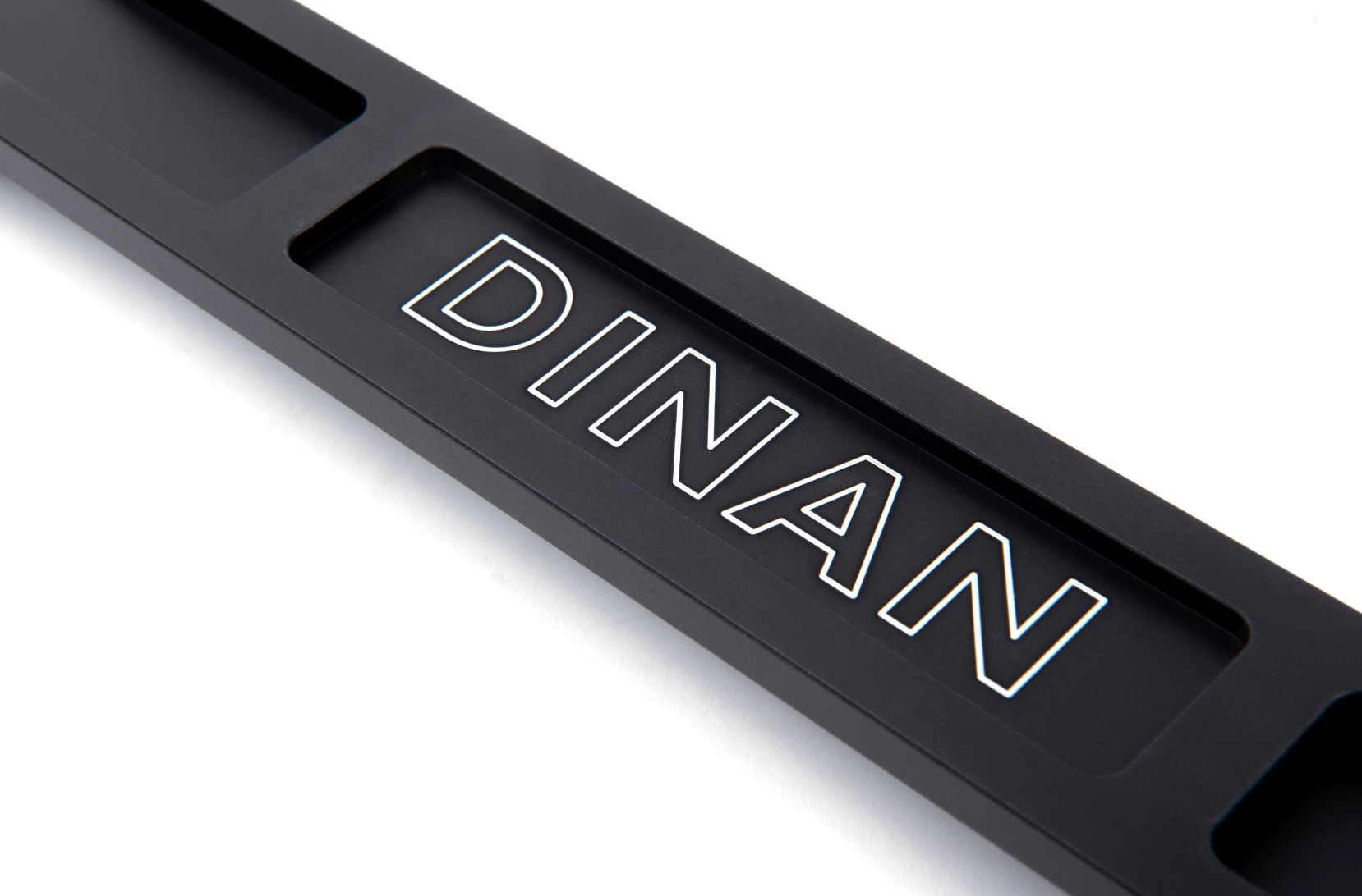 A top close up view of Dinan Strut Tower Braces for BMW with white background  with dinan logo on the brace