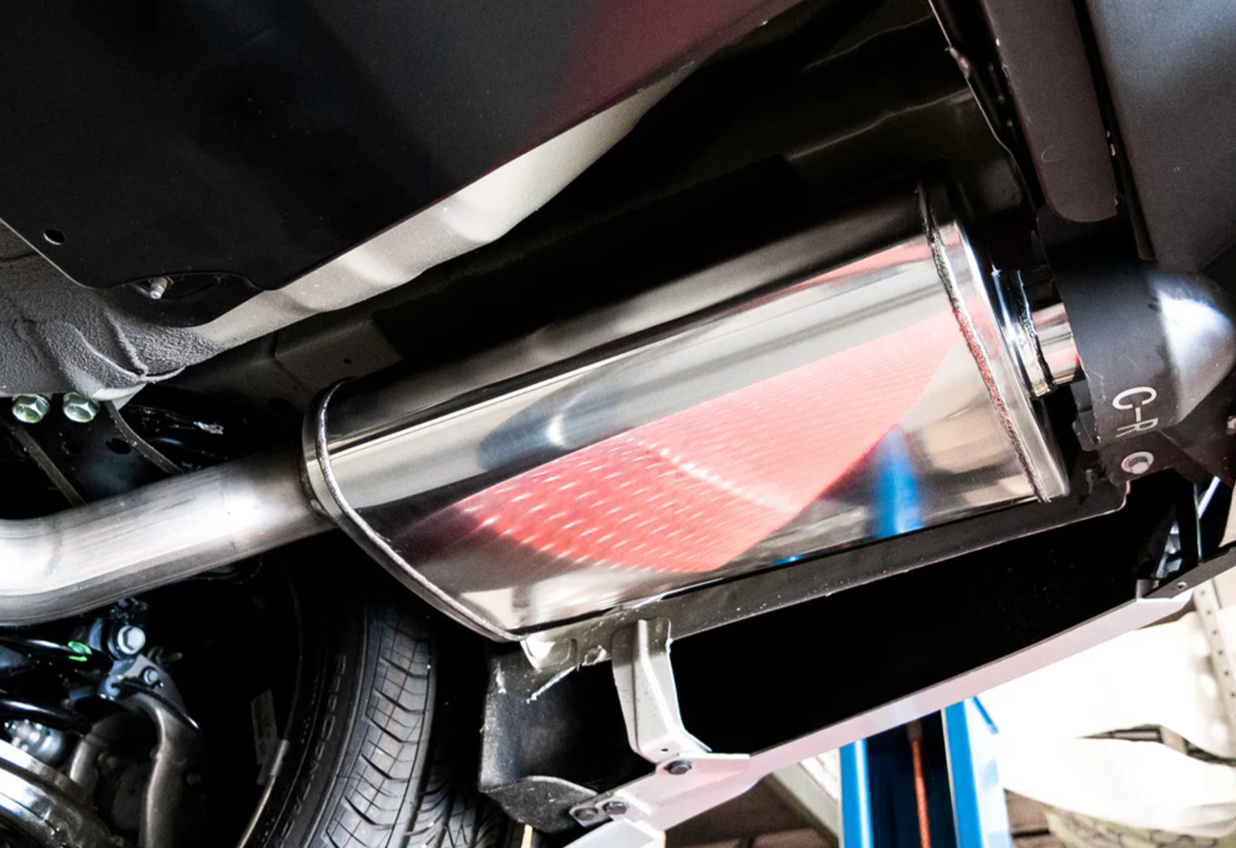 A close up view of the muffler of Stillen Axle-Back Exhaust System for Nissan Maxima [3.5L] 2019-2023 fitted inside a car
