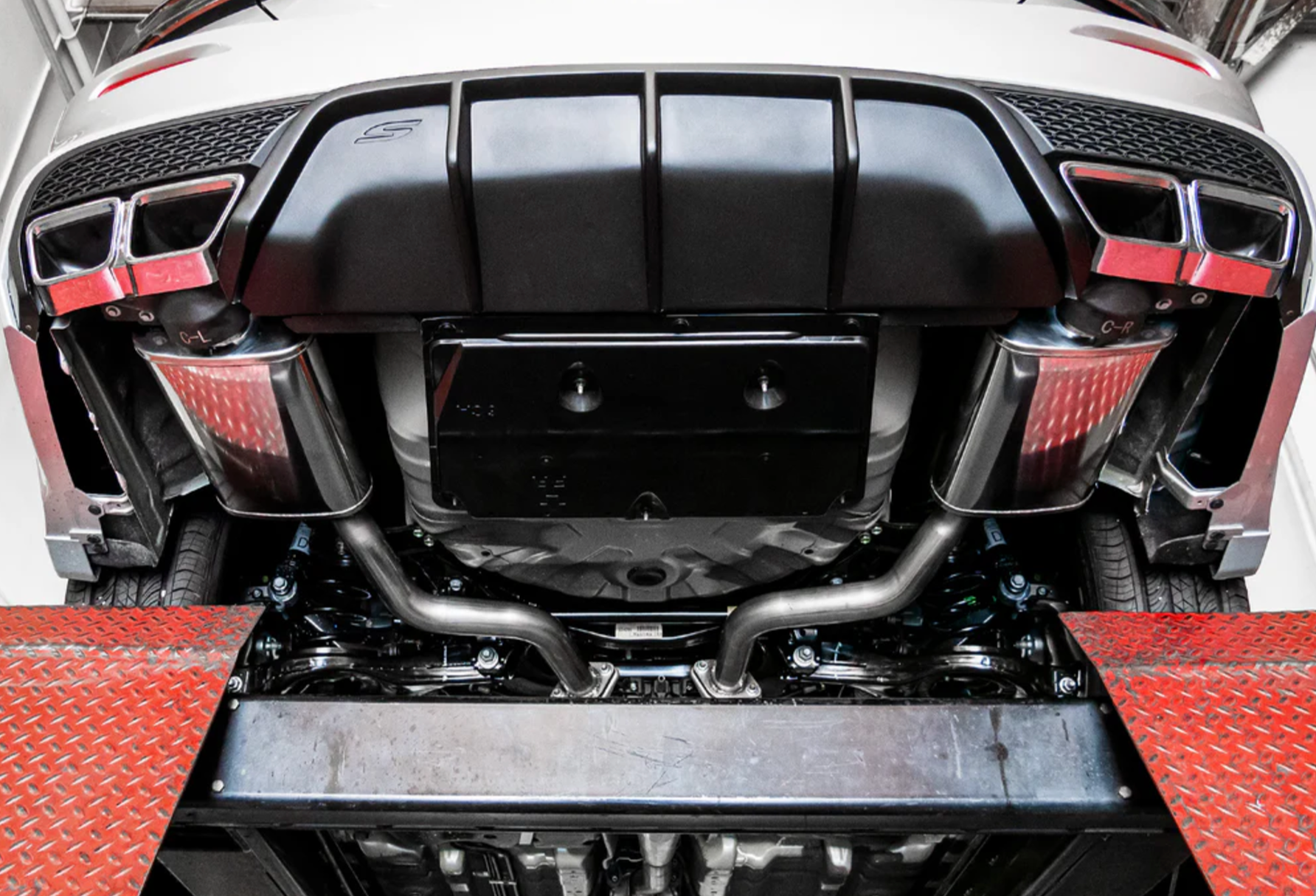 A wider view of Stillen Cat-Back Exhaust System for Nissan Maxima [3.5L] 2019-2023 fitted inside a lifted car