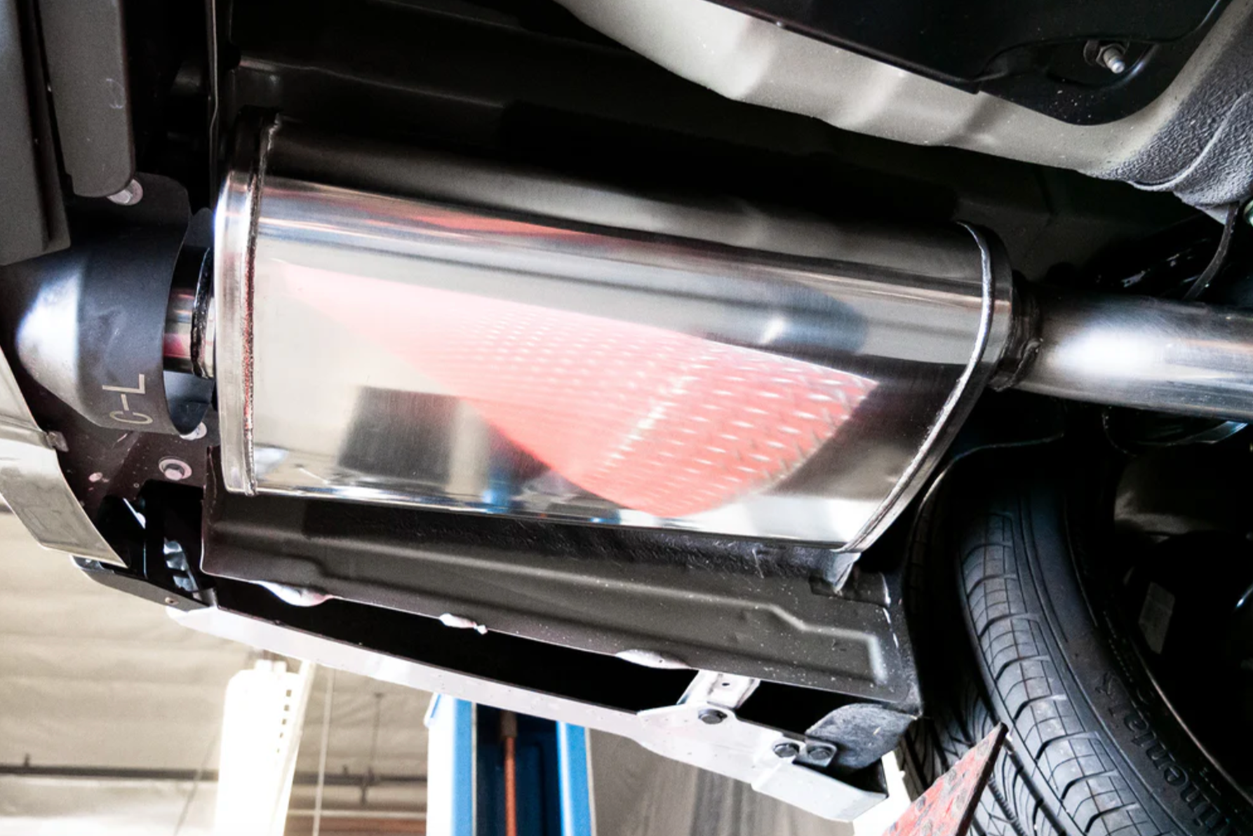 A close up view of the muffler of the Stillen Cat-Back Exhaust System for Nissan Maxima [3.5L] 2019-2023 fitted inside a car