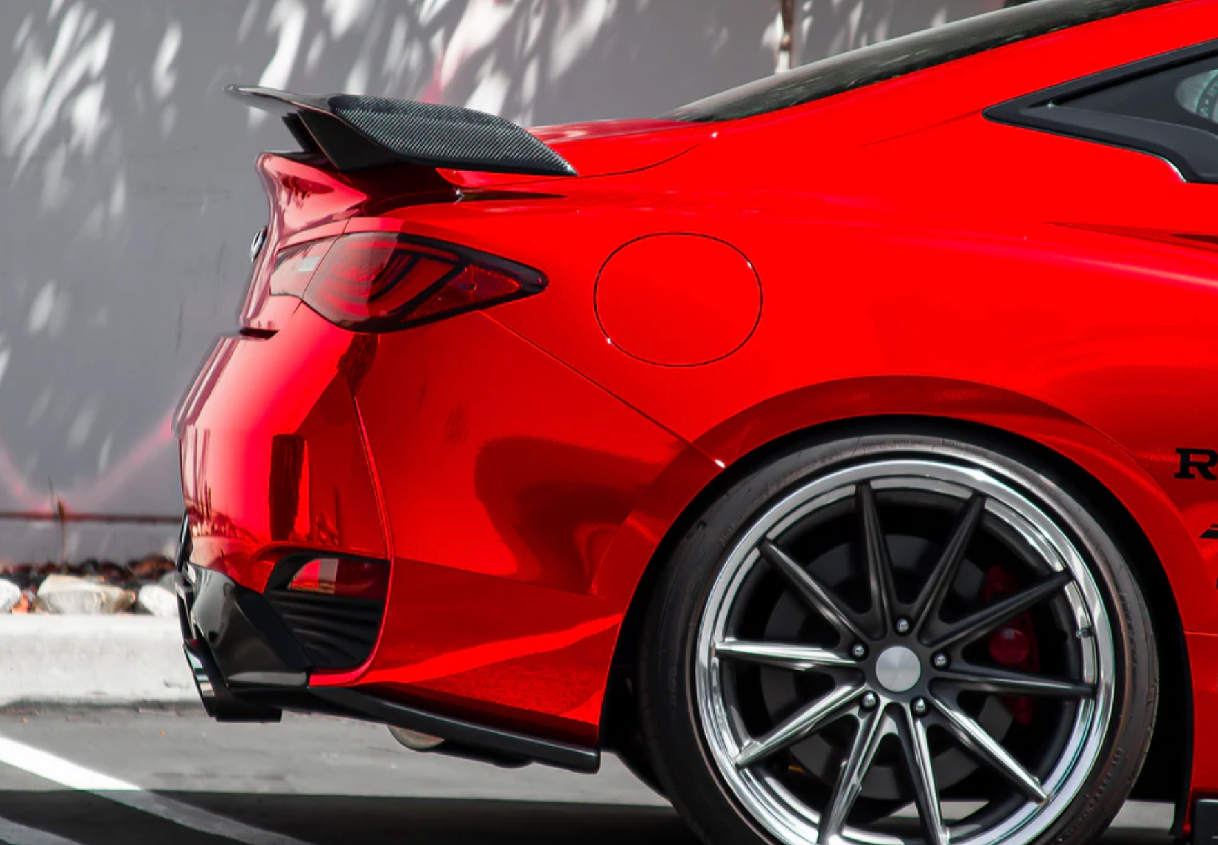 A side close up view of a red car fitted with Stillen Rear Spoiler [Carbon Fiber] for Infiniti Q60 2017-2022