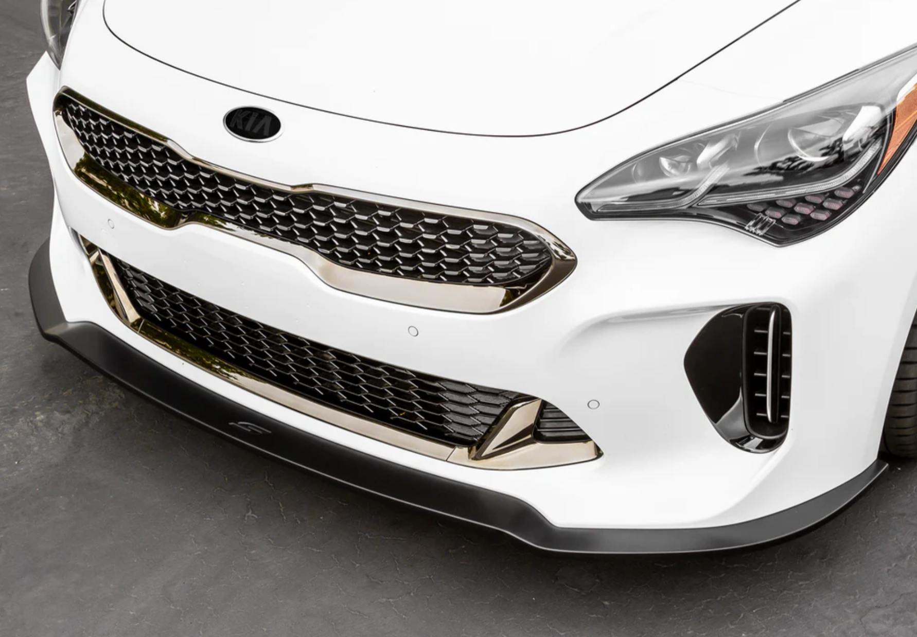A front close up view of a white car on the ground fitted with Stillen Front Splitter [Matte Black] for Kia Stinger GT (AWD/RWD 3.3TT) 2018-2023