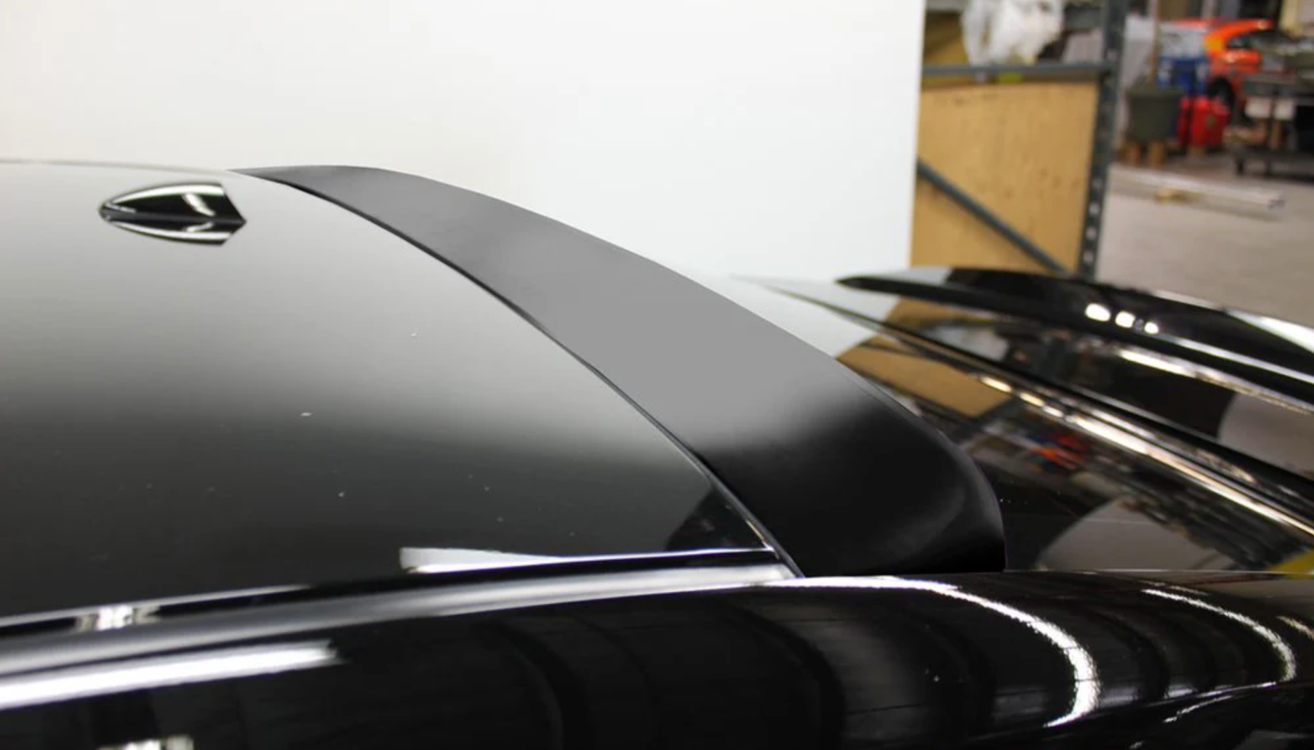 A back close up view of a car fitted with Stillen Roof Wing [Matte Black] for Nissan Maxima 2016-2018 in the garage.