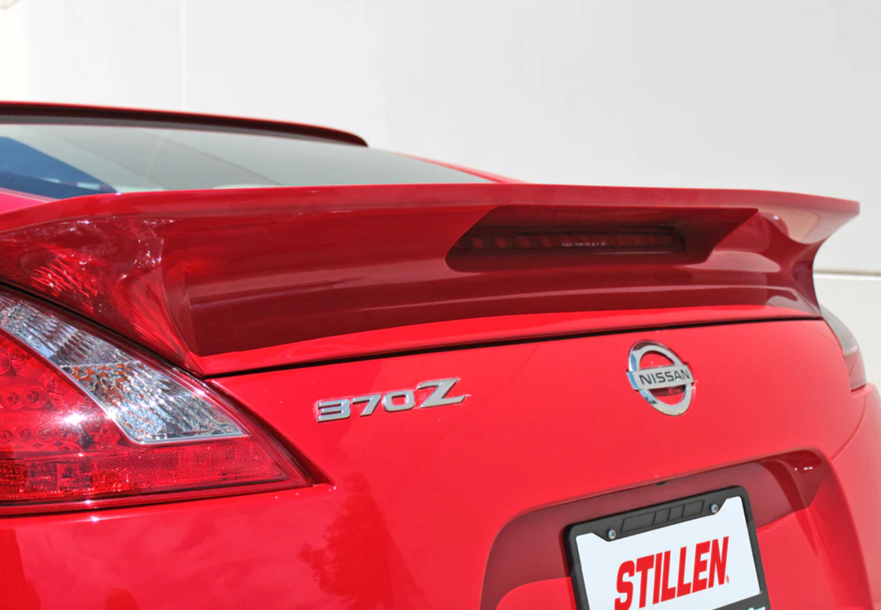 A back close up view of a red car fitted wiith Stillen Rear Wing for Nissan 370Z [Z34] 2009-2020 on a white background