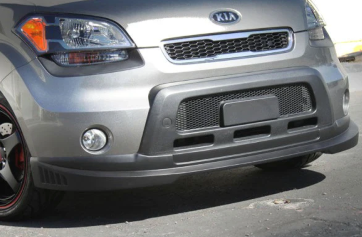 A front close up view of a car fitted with Stillen Front Lip Spoiler for Kia Soul 2010-2011 on the ground