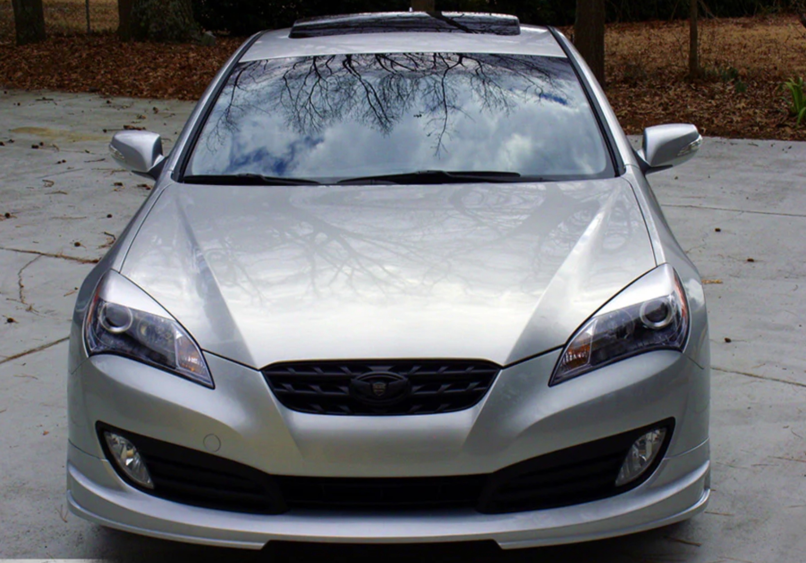 A front wide view of a grey car on the ground fitted with Stillen Front Lip Spoiler for Hyundai Genesis Coupe 2010-2012
