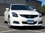 A front wide view of a white car fitted with Stillen Front Lip Spoiler for Nissan Altima Coupe 2010-2013 on the ground