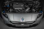 A top wide view of an open bonnet of a car fitted with Eventuri Black Carbon Intake System for BMW F7X M135i M235i / U1X X1 X2 M35i & MINI F6X S JCW 2020-2025 on the ground