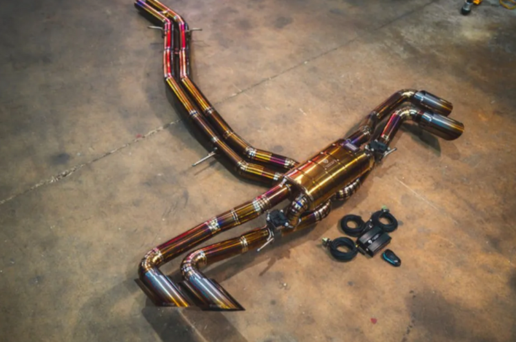 A top wide view of Valvetronic Designs Valved Sport Cat-back Exhaust System for Lamborghini Urus 2018-2025 lying on a concrete ground with all its parts