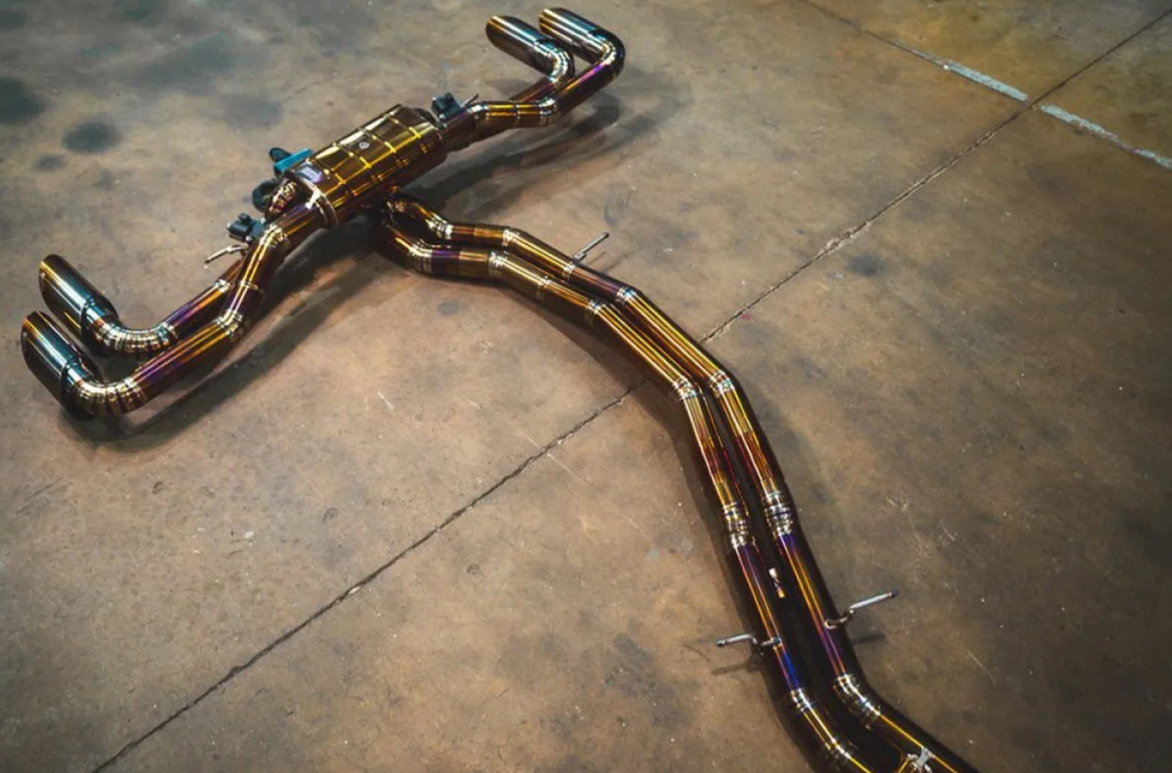 A top back wide view of Valvetronic Designs Valved Sport Cat-back Exhaust System for Lamborghini Urus 2018-2025 lying on a concrete ground