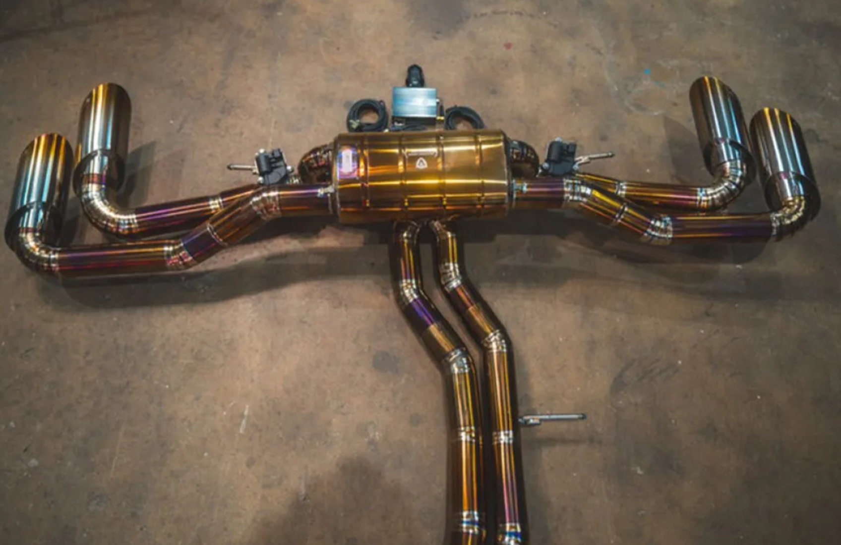 A close up top view of Valvetronic Designs Valved Sport Cat-back Exhaust System for Lamborghini Urus 2018-2025 lying on a concrete ground