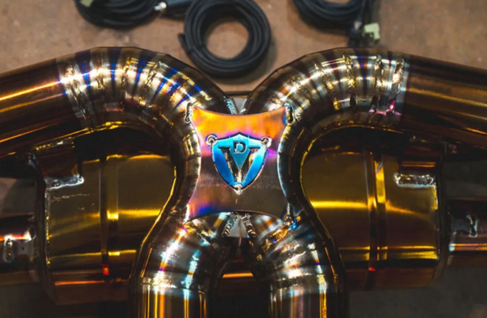 A close up view of Valvetronic Designs logo on the Valved Sport Cat-back Exhaust System for Lamborghini Urus 2018-2025 lying on a concrete ground