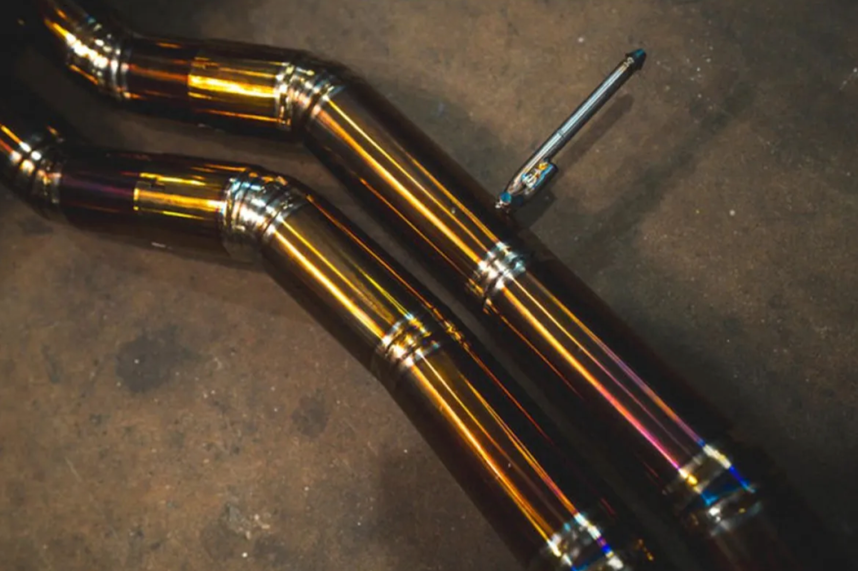 A close up view of the pipes of Valvetronic Designs Valved Sport Cat-back Exhaust System for Lamborghini Urus 2018-2025 lying on a concrete ground