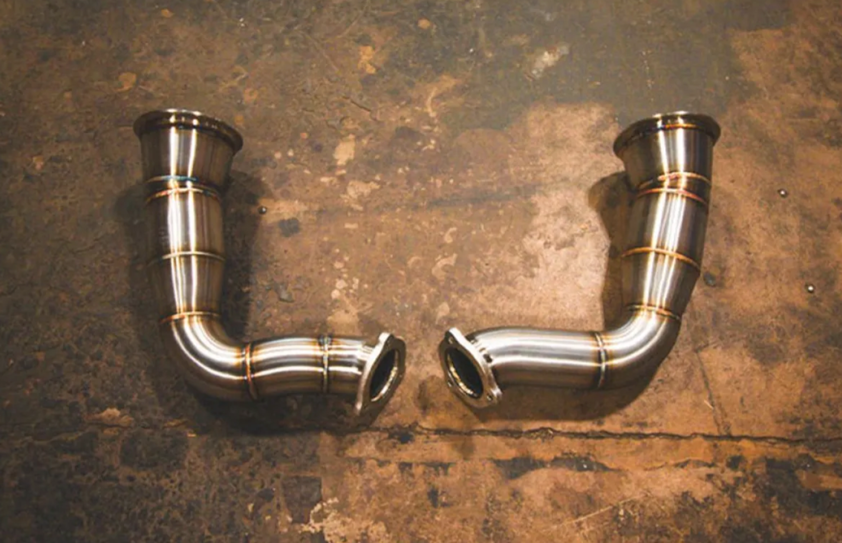 A top wide view of exhaust pipes of Valvetronic Designs Valved Sport Cat-back Exhaust System for Lamborghini Urus 2018-2025 lying on a concrete ground