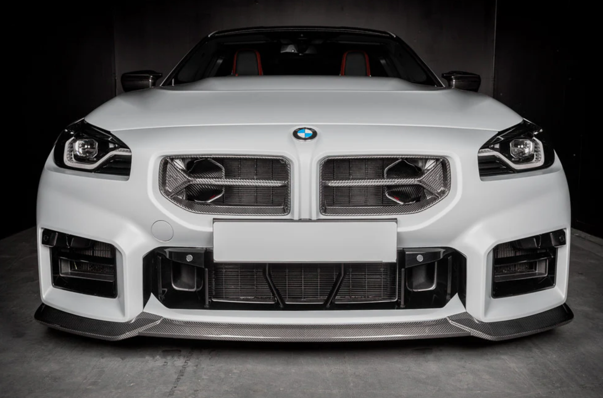 A front wide view of a white car fitted with Eventuri Black Carbon Intake Scoop Set for BMW G87 M2 2023-2025