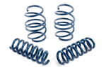 A complete set of four dark blue performance coil springs, with two standing vertically in the back and two lying horizontally in the front on a white background.