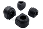 A close-up of four black rubber bushings, with some featuring part numbers and the "DINAN" logo engraved on the top surface.