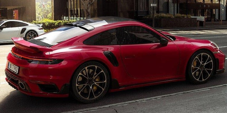 A wide side view of TECHART Roof Spoiler Porsche 992 Carrera & Turbo fitted on a red car on the road