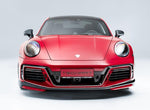 A front wide view of TECHART Front Bumper Porsche 992 Turbo /S fitted on a red Porsche with a white background