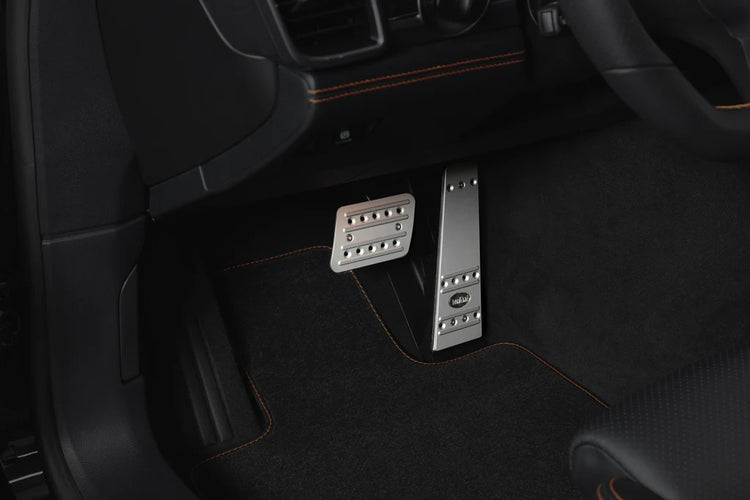 A close up view of TECHART Pedal-Kit, Aluminum Silver Tiptronic/PDK for Porsche 987/981/718 / 997/991 /970 fitted in a car with the pedals highlighted