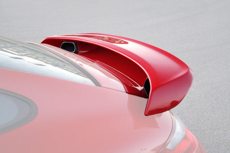 A close up view of TECHART Rear Spoiler II for Porsche 997 Turbo fitted on a red car with the spoiler highlighted 