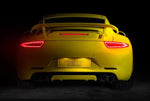 A back wide view of TECHART Rear Diffuser Add-on Porsche 991.1 Carrera / Targa fitted on a yellow Porsche with a black background