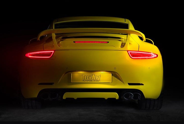 A back wide view of TECHART Rear Diffuser Add-on Porsche 991.1 Carrera / Targa fitted on a yellow Porsche with a black background