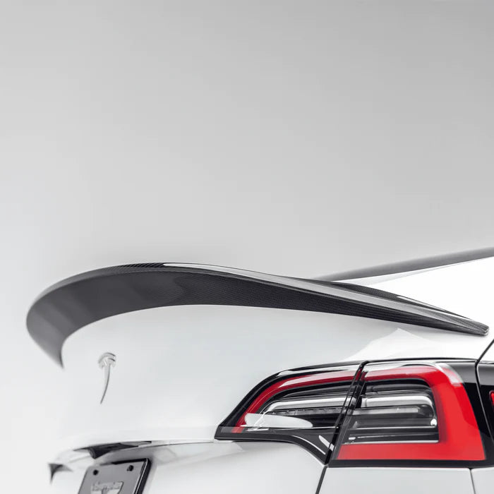 A close up view of Vorsteiner VRS Aero Decklid Spoiler Carbon Fiber PP 2x2 Glossy fitted on a white car (for Model Y).