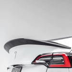 A close up view of Vorsteiner VRS Aero Decklid Spoiler Carbon Fiber PP 2x2 Glossy fitted on a white car (for Model Y).