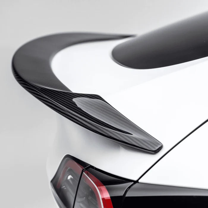 A close up view of Vorsteiner VRS Aero Decklid Spoiler Carbon Fiber PP 2x2 Glossy fitted on a white car (for Model Y).