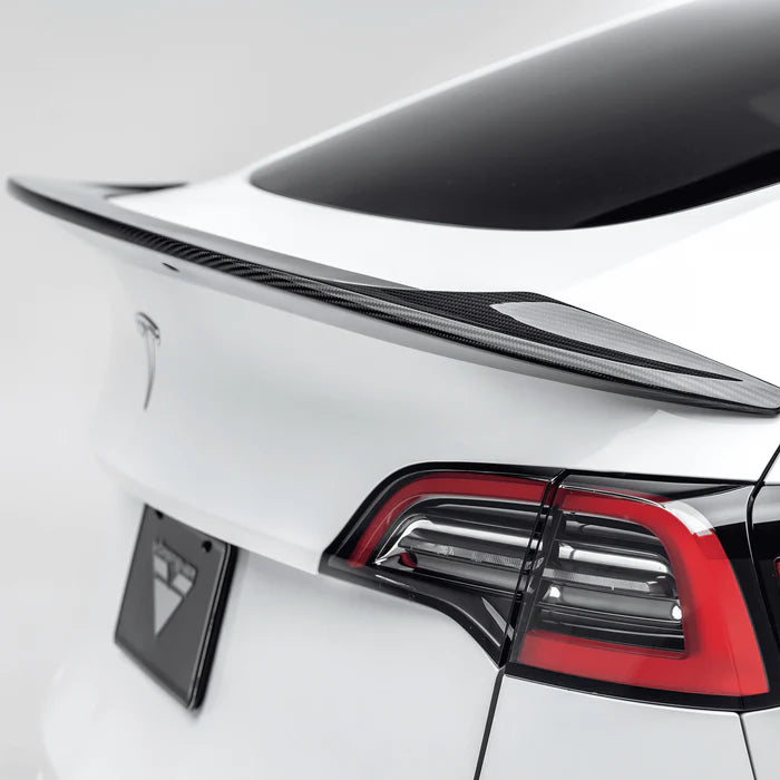 A close up view of Vorsteiner VRS Aero Decklid Spoiler Carbon Fiber PP 2x2 Glossy fitted on a white car (for Model Y).